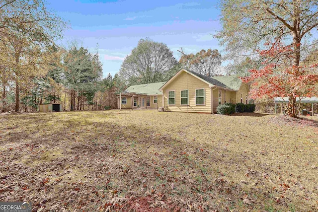 rear view of house with a yard and a storage shed