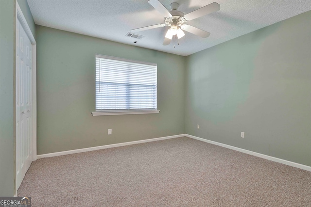 carpeted empty room featuring a textured ceiling and ceiling fan