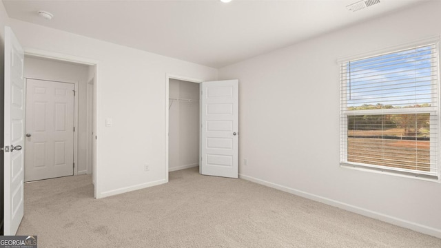 unfurnished bedroom with light colored carpet and a closet