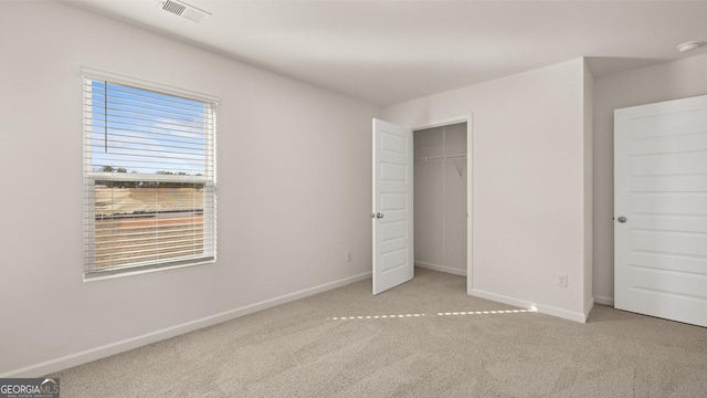 unfurnished bedroom featuring light colored carpet and a closet