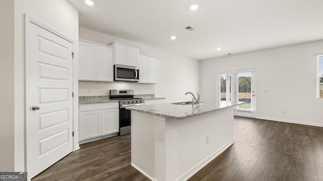 kitchen with white cabinetry, an island with sink, dark hardwood / wood-style floors, and appliances with stainless steel finishes