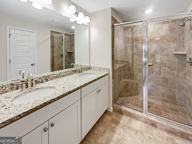 bathroom featuring a shower with shower door, vanity with extensive cabinet space, dual sinks, and tile floors