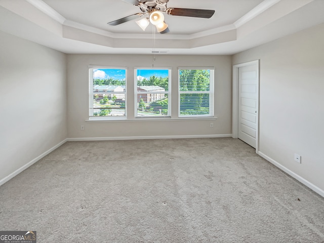 carpeted empty room featuring ornamental molding, ceiling fan, and a raised ceiling