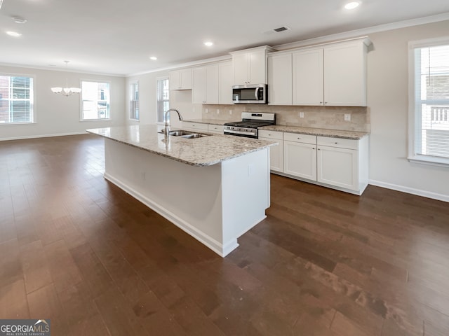 kitchen with dark hardwood / wood-style flooring, a healthy amount of sunlight, a kitchen island with sink, and appliances with stainless steel finishes