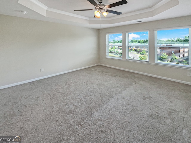 empty room with carpet floors, ceiling fan, and a raised ceiling