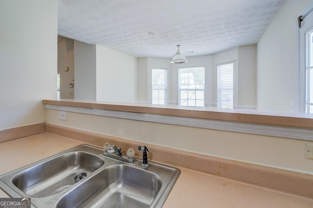 kitchen with a textured ceiling, pendant lighting, and sink