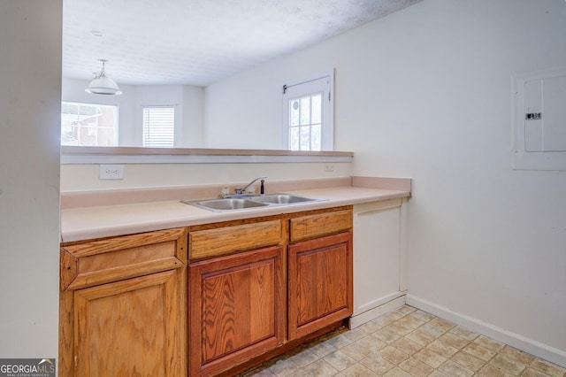 kitchen with electric panel, plenty of natural light, hanging light fixtures, and sink