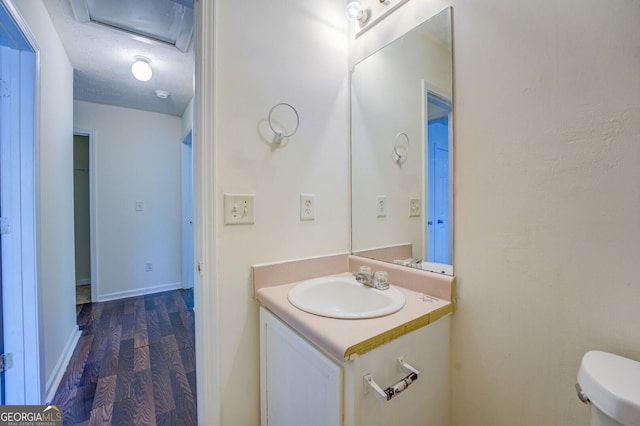 bathroom featuring hardwood / wood-style floors, vanity, toilet, and a textured ceiling