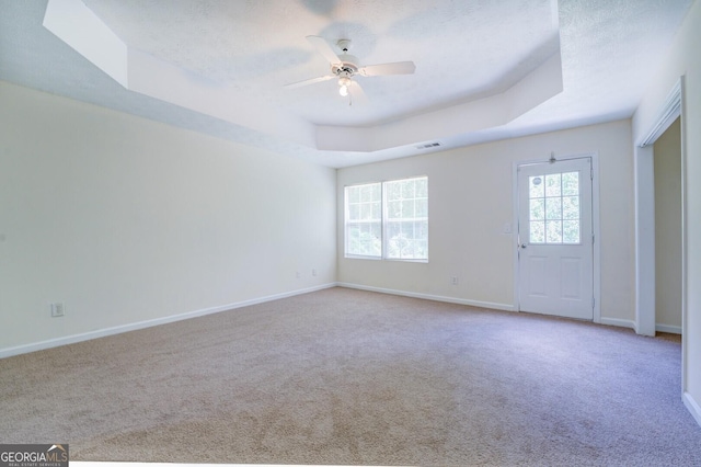 carpeted empty room with ceiling fan, a raised ceiling, and a textured ceiling