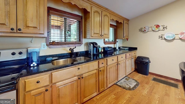 kitchen with light hardwood / wood-style floors, sink, range, and dark stone counters