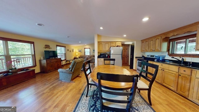 kitchen with light hardwood / wood-style floors, stainless steel range, sink, white fridge, and vaulted ceiling