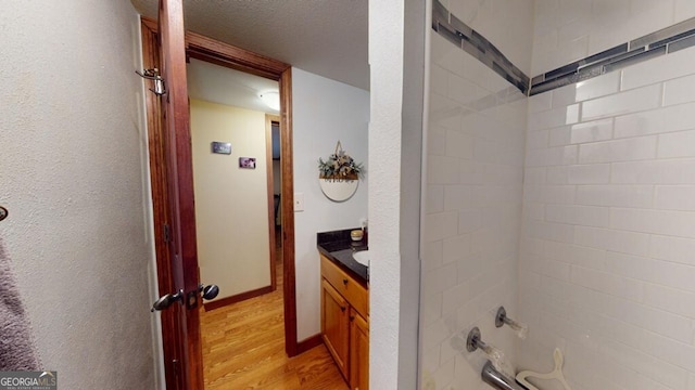 bathroom featuring shower / bath combination, wood-type flooring, vanity, and a textured ceiling