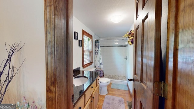 bathroom featuring walk in shower, wood-type flooring, toilet, and vanity