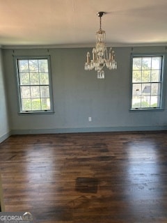 spare room with dark hardwood / wood-style floors, an inviting chandelier, and crown molding