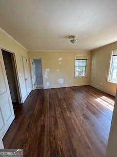 spare room with crown molding, a wealth of natural light, and dark hardwood / wood-style floors