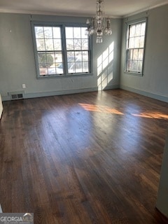 unfurnished dining area featuring dark hardwood / wood-style floors, plenty of natural light, crown molding, and a chandelier