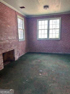 unfurnished living room featuring brick wall, a fireplace, and crown molding