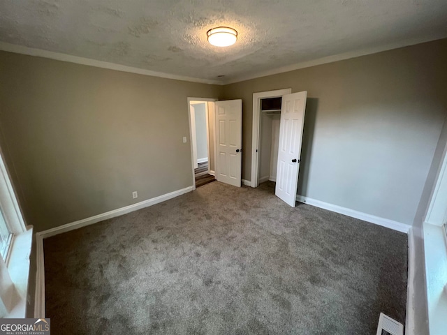 unfurnished bedroom featuring a textured ceiling, ornamental molding, and carpet