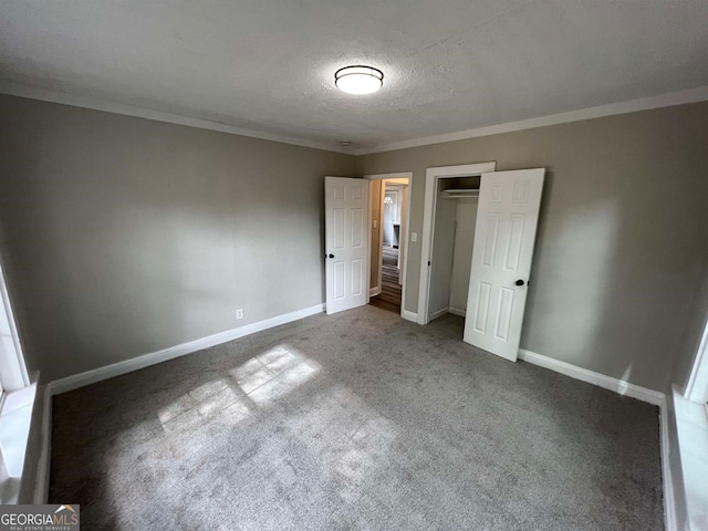 unfurnished bedroom with a closet, carpet, ornamental molding, and a textured ceiling