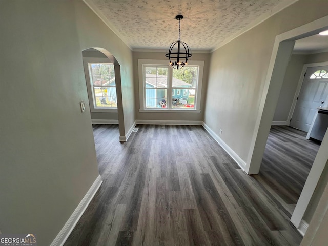 unfurnished dining area with a notable chandelier, a textured ceiling, dark wood-type flooring, and ornamental molding