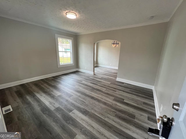 empty room featuring wood-type flooring, ornamental molding, and a textured ceiling