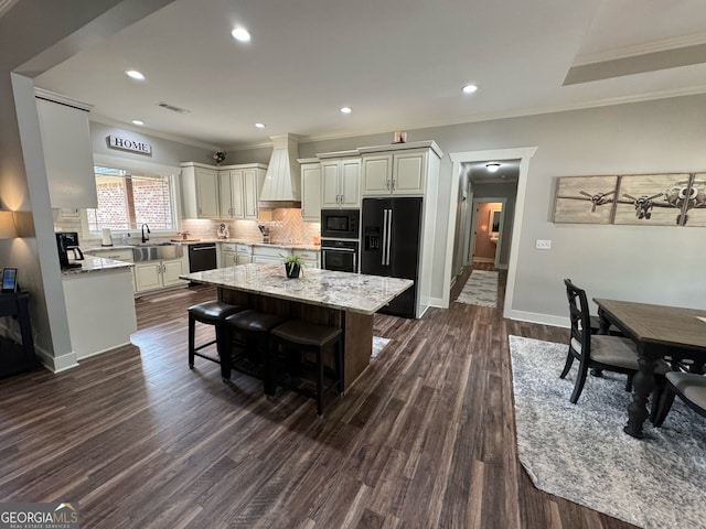 kitchen with wall chimney range hood, light stone countertops, dark hardwood / wood-style flooring, black appliances, and a breakfast bar