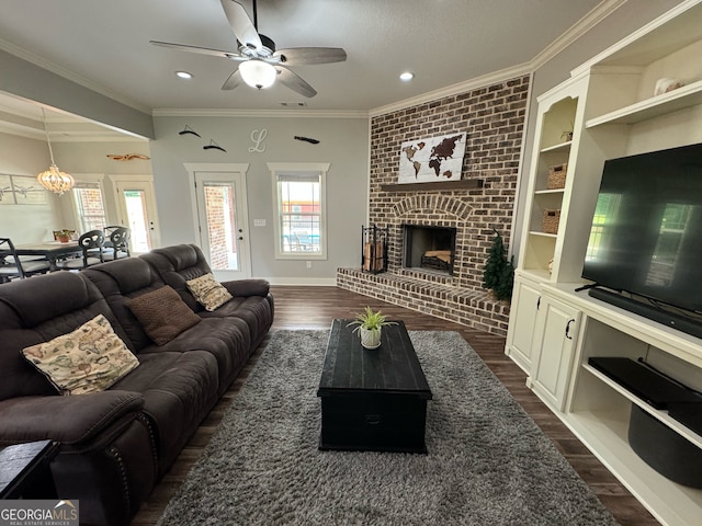 living room featuring brick wall, ornamental molding, a fireplace, dark hardwood / wood-style flooring, and ceiling fan