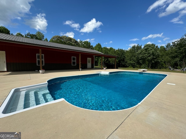 view of swimming pool with a patio area and a diving board