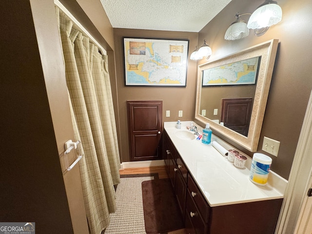 bathroom with a textured ceiling, vanity, and walk in shower