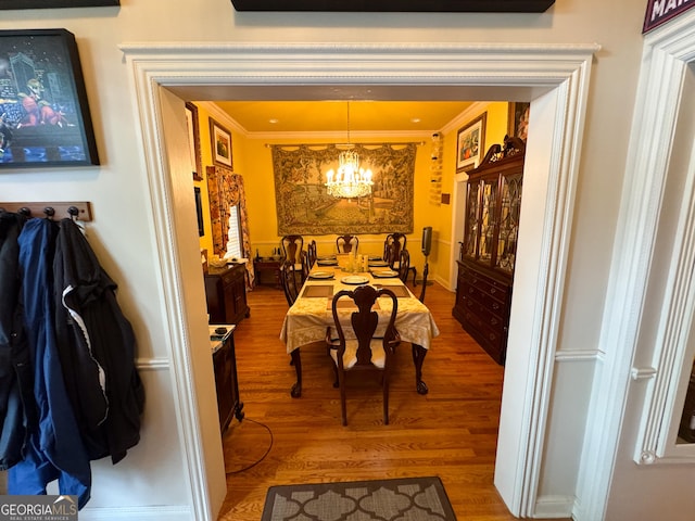 dining room featuring crown molding, wood-type flooring, and a notable chandelier