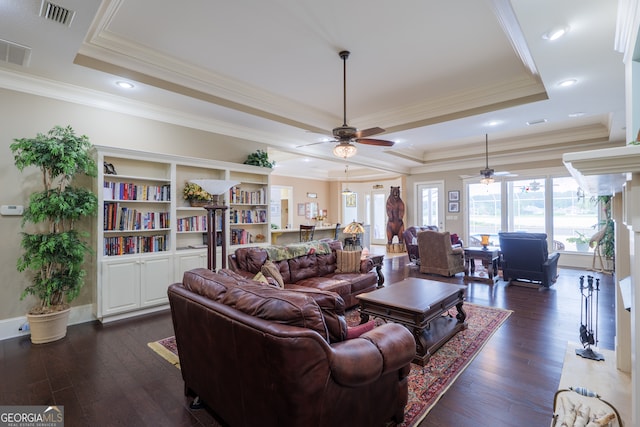 living room with a tray ceiling, ceiling fan, dark hardwood / wood-style floors, and crown molding