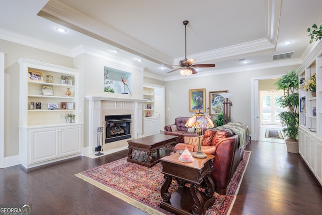 living room featuring dark wood-type flooring, ceiling fan, and a tray ceiling