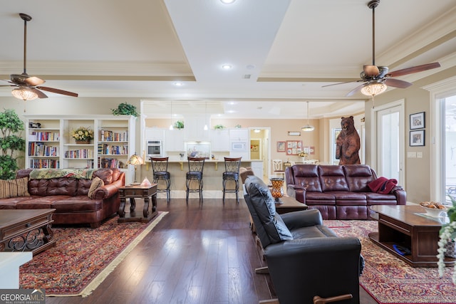 living room featuring a tray ceiling, crown molding, ceiling fan, and dark hardwood / wood-style flooring