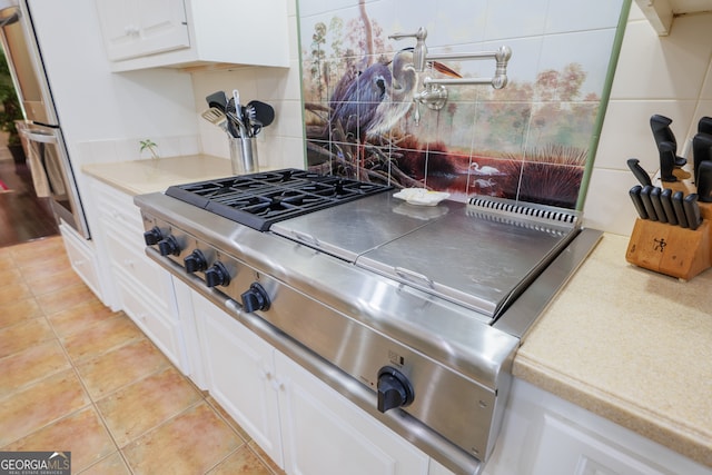 kitchen with range, tasteful backsplash, white cabinetry, and light tile floors