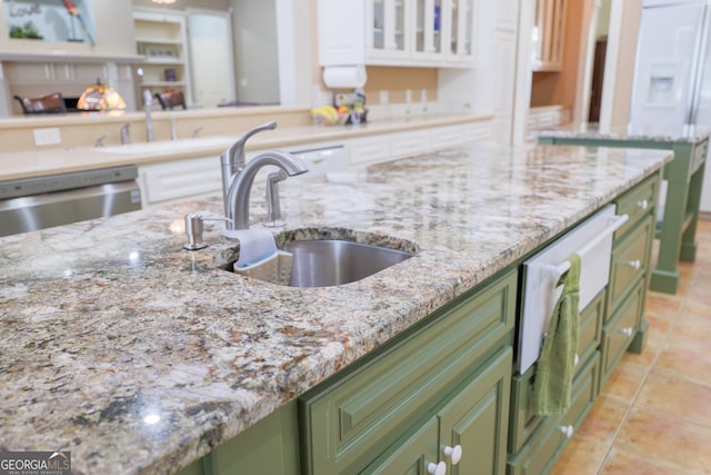 kitchen with green cabinets, white cabinetry, sink, and light stone countertops