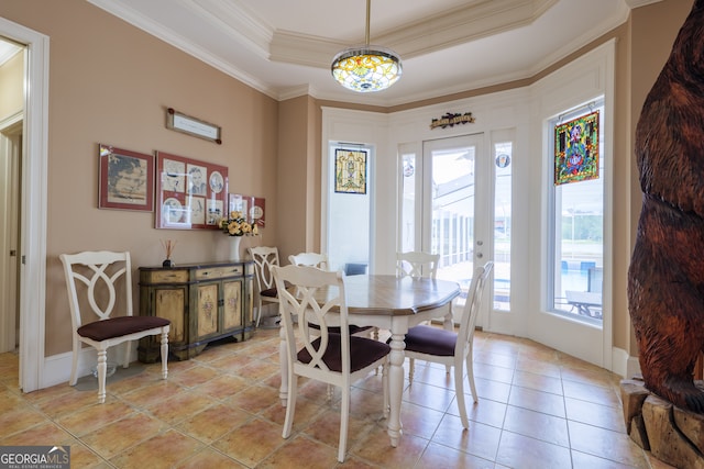 tiled dining room with ornamental molding and a tray ceiling