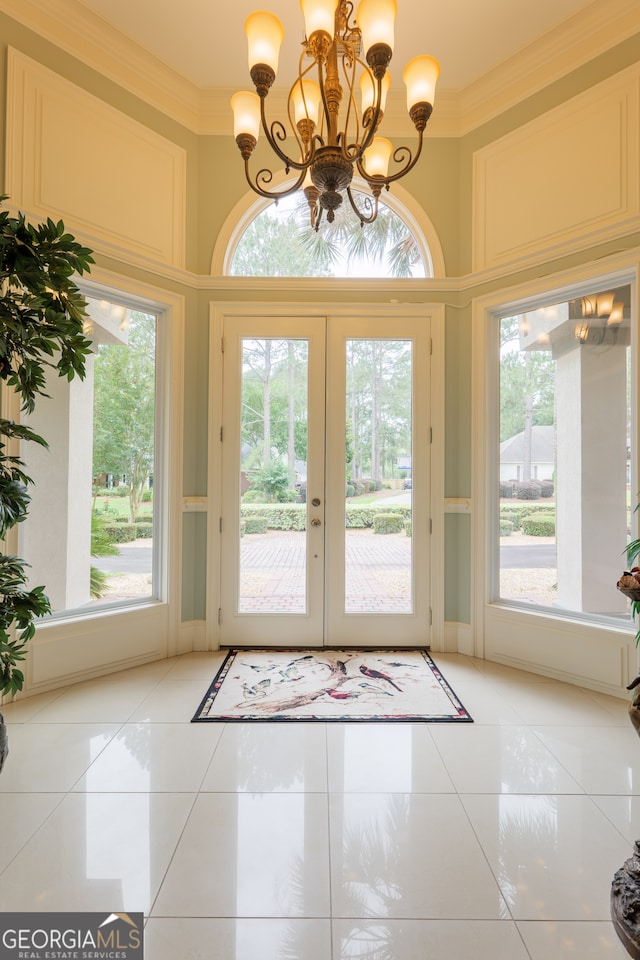 doorway to outside featuring french doors, ornamental molding, light tile floors, and an inviting chandelier