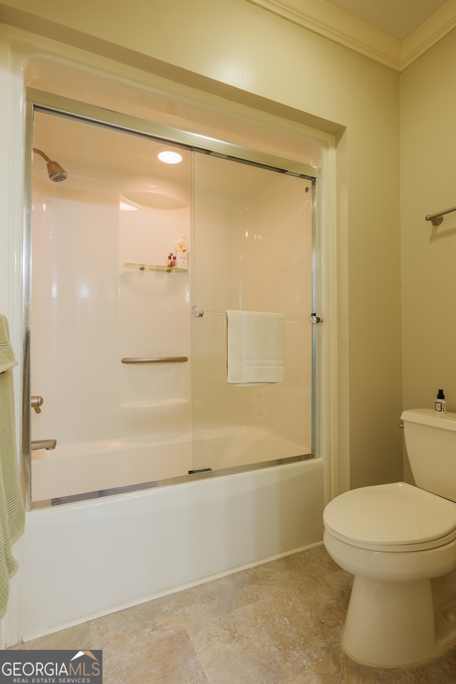 bathroom featuring tile flooring, ornamental molding, combined bath / shower with glass door, and toilet