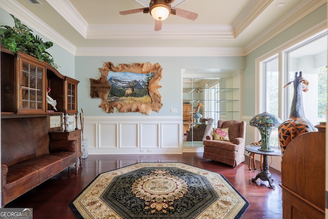 sitting room with ornamental molding, dark wood-type flooring, ceiling fan, and a raised ceiling