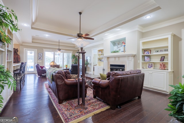 living room featuring a raised ceiling, ornamental molding, ceiling fan, and dark hardwood / wood-style floors