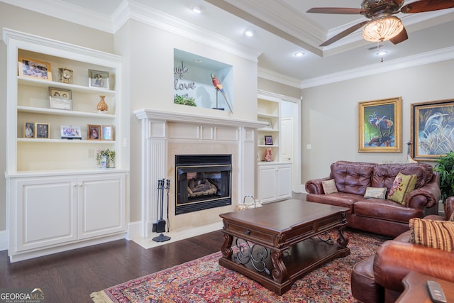 living room with crown molding, a high end fireplace, dark hardwood / wood-style flooring, built in shelves, and ceiling fan