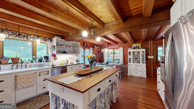 kitchen with appliances with stainless steel finishes, pendant lighting, white cabinetry, and a kitchen island