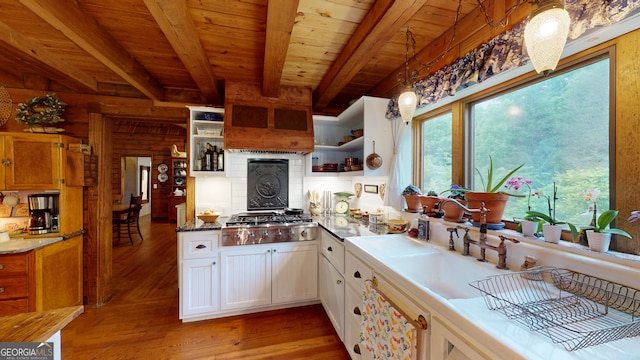 kitchen with stainless steel gas stovetop, light hardwood / wood-style floors, hanging light fixtures, beam ceiling, and white cabinets