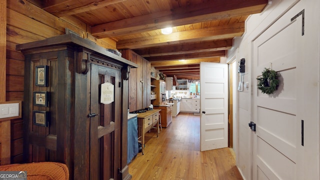 hallway with beam ceiling, light wood-type flooring, wood ceiling, and wooden walls