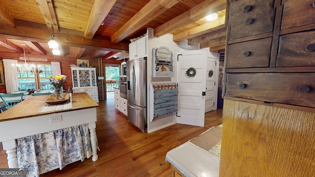 kitchen featuring stainless steel appliances, a center island, decorative light fixtures, white cabinets, and beamed ceiling