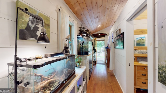 hallway featuring light wood-type flooring, wooden ceiling, and vaulted ceiling