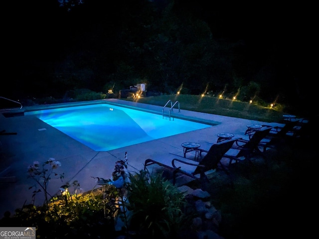 view of pool at twilight