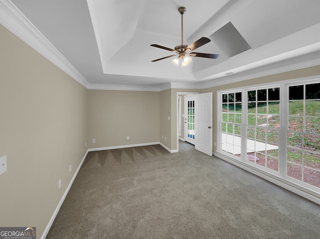 carpeted empty room with ornamental molding, ceiling fan, and a raised ceiling