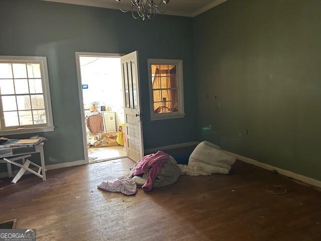 bedroom with crown molding, hardwood / wood-style flooring, and a chandelier