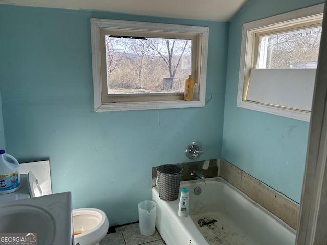 bathroom with a bath, vanity, a healthy amount of sunlight, and tile patterned flooring